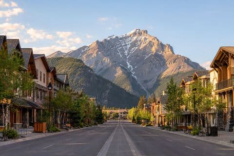 Banff Avenue in the early evening, shopfronts lit and Cascade Mountain closing the end of the street.