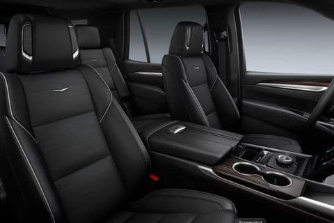 The front seats and centre console of the Escalade, wood trim around the gear selector and cupholders.