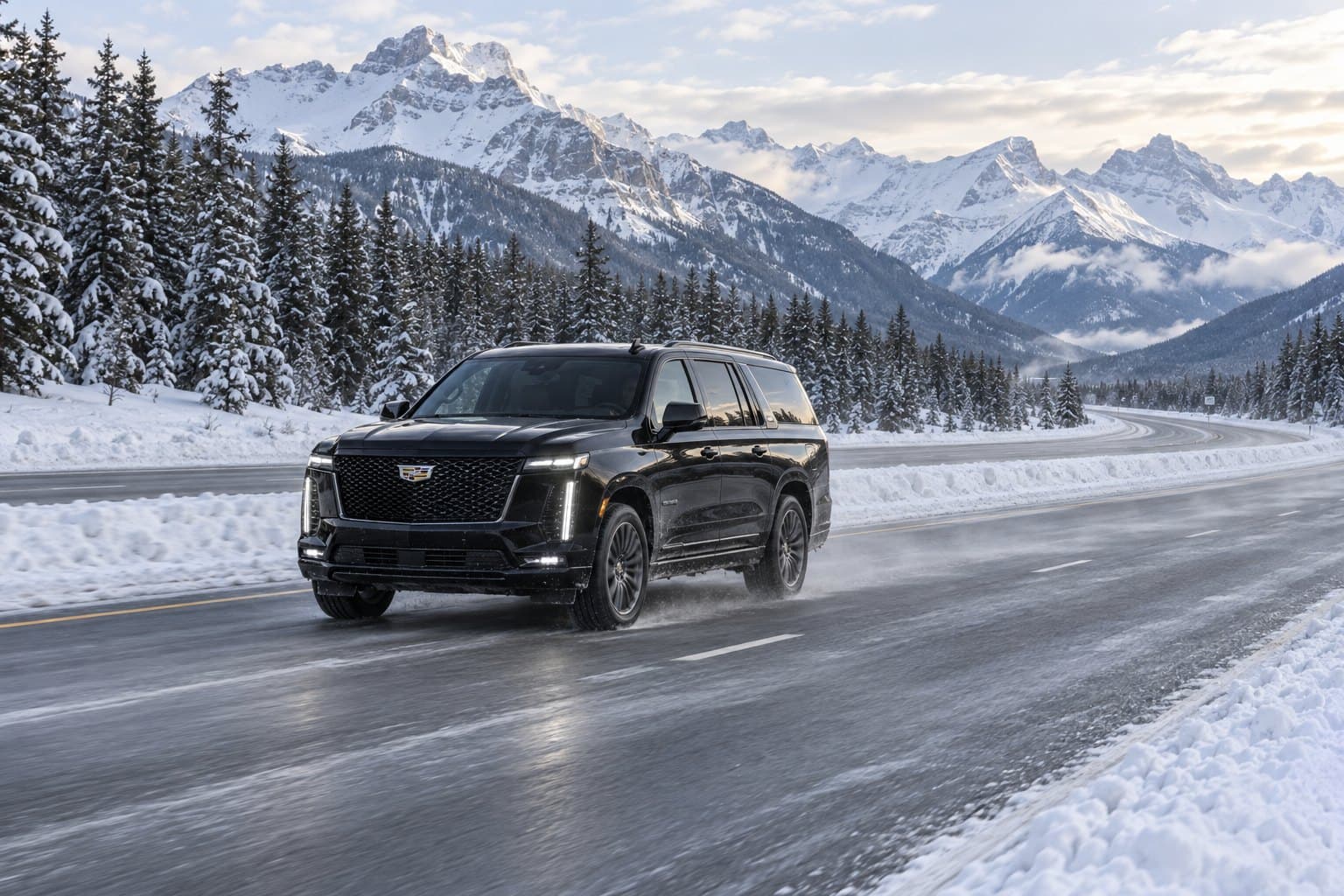 A black Cadillac Escalade on a plowed mountain highway in winter, snow-covered pines and peaks behind.